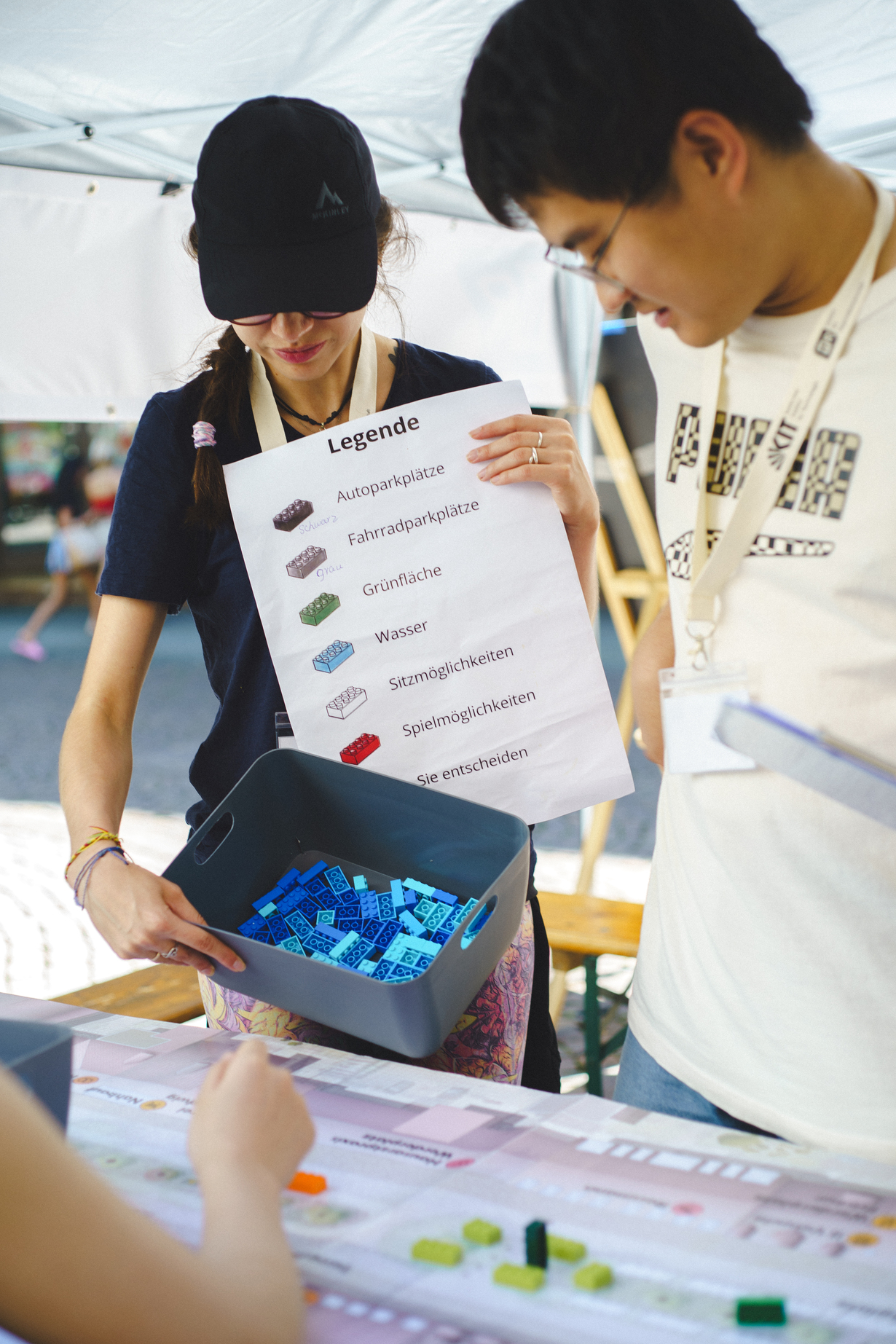 Forschende zeigen Legende zu farbigen Legobausteinen an einem Stand